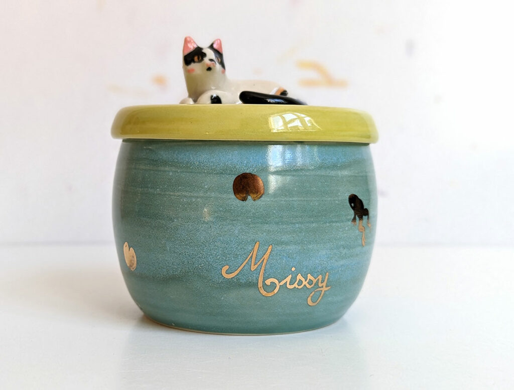 Blue and green urn with gold lily pads as this cat used to rest near a pond with frogs