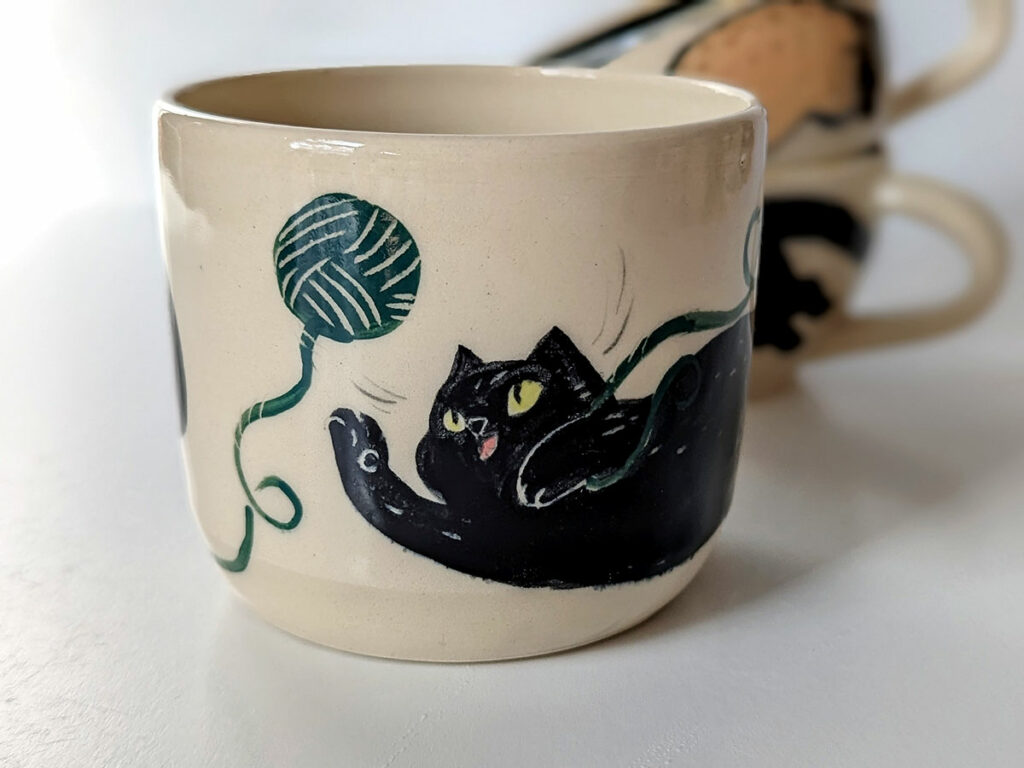 cup cat playing with yarn